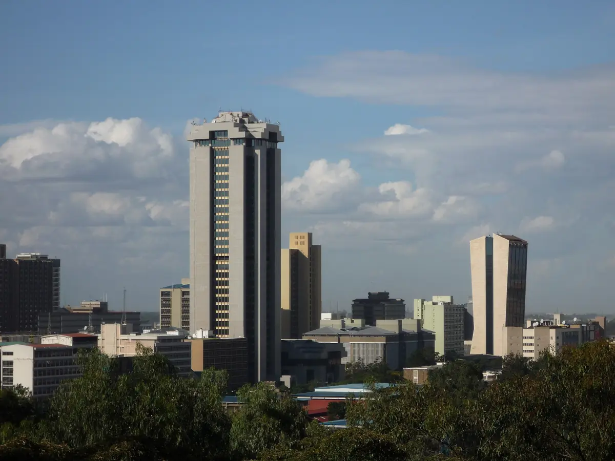 Hoogbouw in het centrum van Nairobi onder een blauwe hemel met verspreide wolken en groene bomen