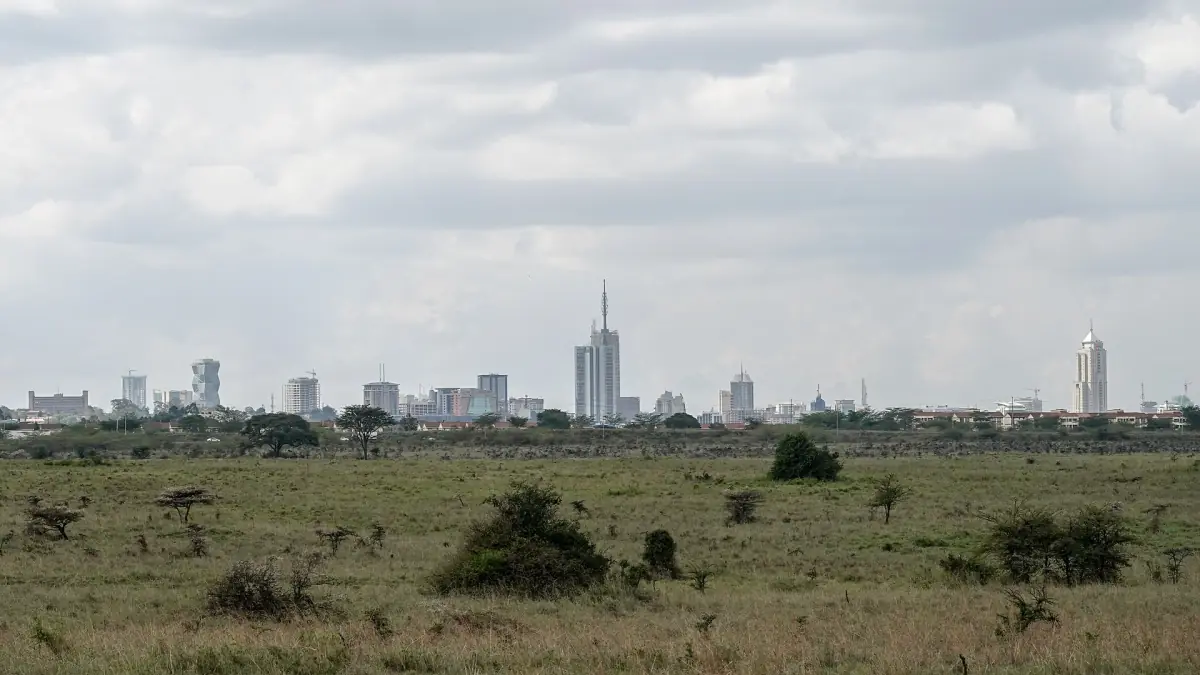 Nairobi skyline rising above open savanna and scattered acacia bushes