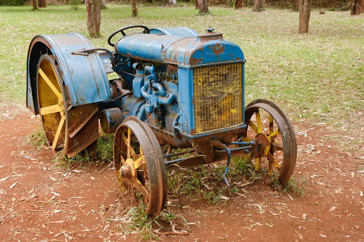 Oude blauwe tractor met gele wielen op rode aarde op het museumterrein